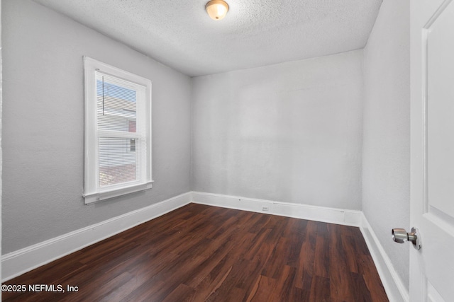 empty room featuring a textured ceiling and dark hardwood / wood-style flooring