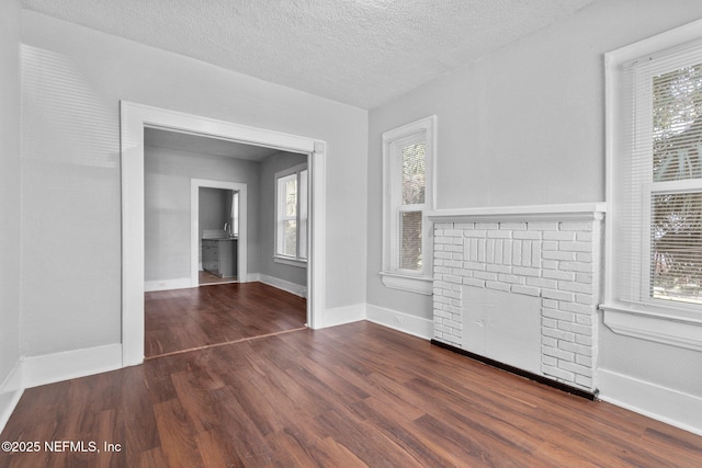 unfurnished living room featuring a textured ceiling, a fireplace, and dark hardwood / wood-style floors