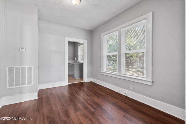 empty room featuring sink, dark wood-type flooring, and a textured ceiling