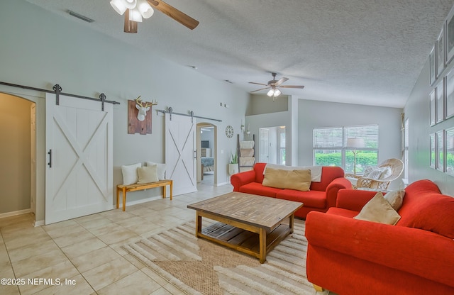 tiled living room featuring a textured ceiling, a barn door, ceiling fan, and lofted ceiling