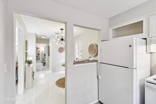 kitchen featuring stove, white fridge, and an inviting chandelier