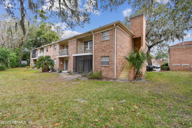 rear view of house featuring a sunroom, a balcony, and a lawn