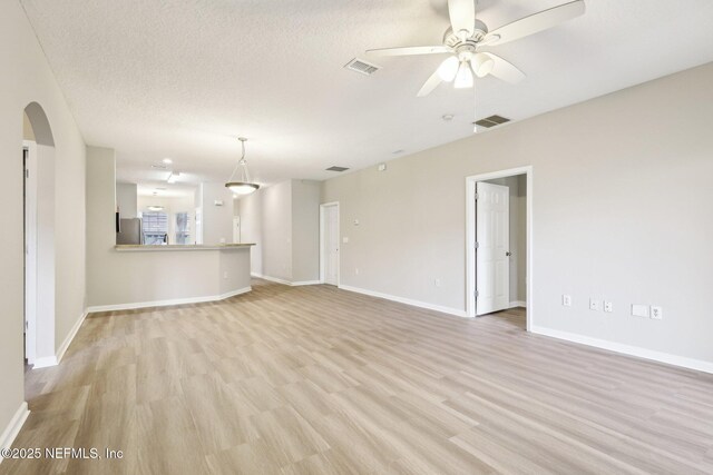 unfurnished living room with a textured ceiling, ceiling fan, and light hardwood / wood-style flooring