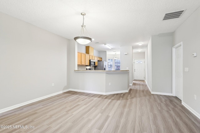 unfurnished living room with a textured ceiling and light wood-type flooring