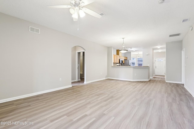 unfurnished living room featuring a textured ceiling, ceiling fan, and light wood-type flooring