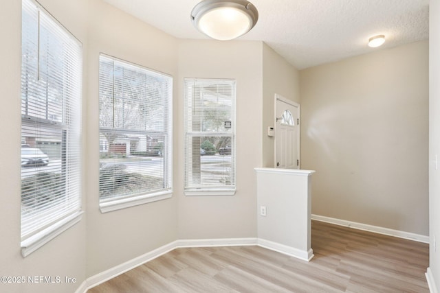 unfurnished room with a textured ceiling and light wood-type flooring