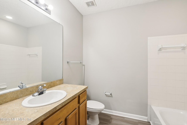 bathroom with vanity, toilet, hardwood / wood-style floors, and a textured ceiling