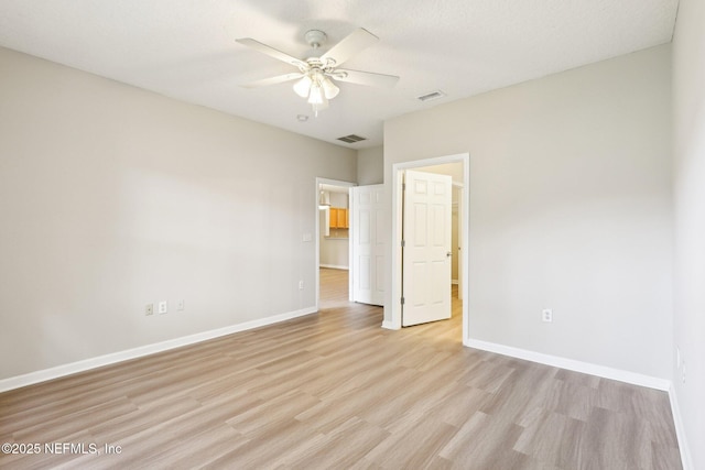 unfurnished bedroom with ceiling fan, a walk in closet, and light wood-type flooring