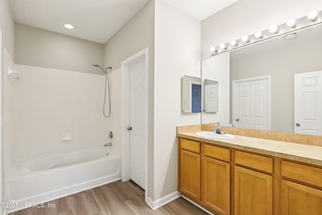 bathroom with wood-type flooring, tub / shower combination, vanity, and a textured ceiling