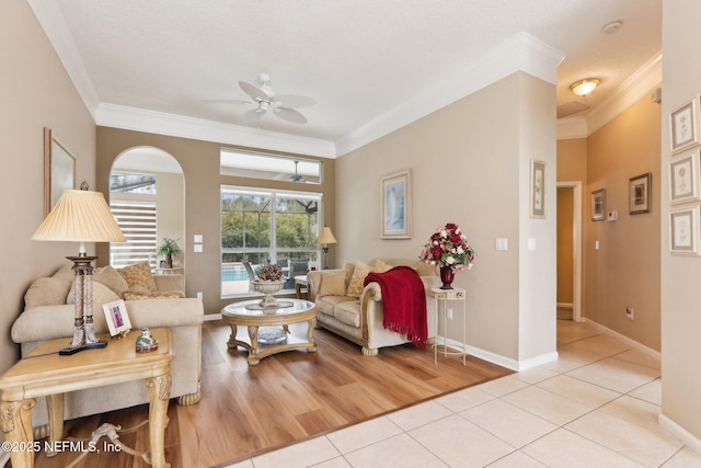 tiled living room with crown molding and ceiling fan