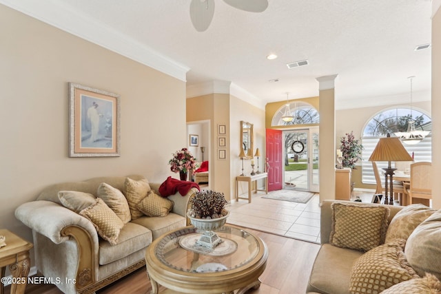 living room with crown molding, ceiling fan with notable chandelier, and light hardwood / wood-style floors