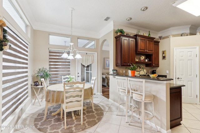 kitchen with ornamental molding, light tile patterned floors, a notable chandelier, and decorative light fixtures