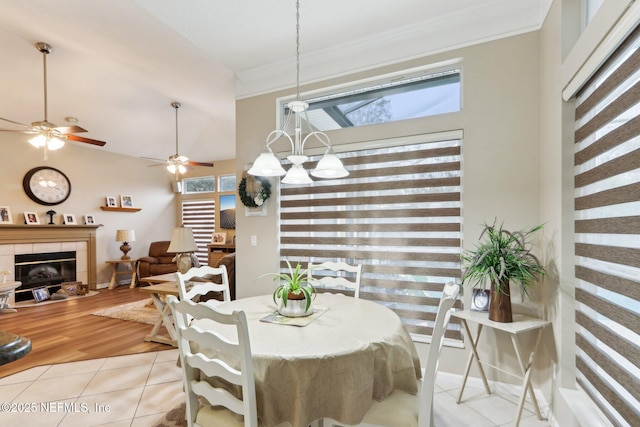 dining room featuring a tile fireplace, light tile patterned flooring, vaulted ceiling, and ornamental molding