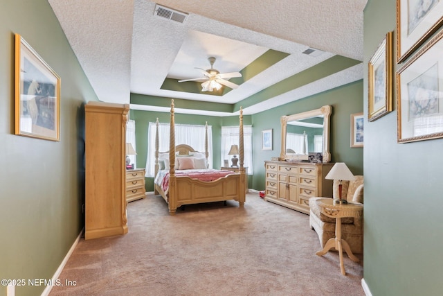 carpeted bedroom with a raised ceiling, ceiling fan, and a textured ceiling