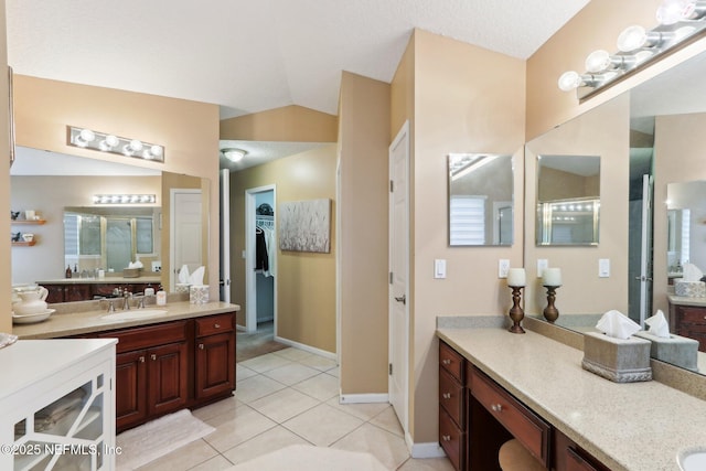 bathroom featuring vaulted ceiling, vanity, a shower with door, and tile patterned flooring