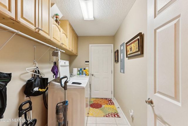 clothes washing area with light tile patterned floors, cabinets, washer and dryer, and a textured ceiling