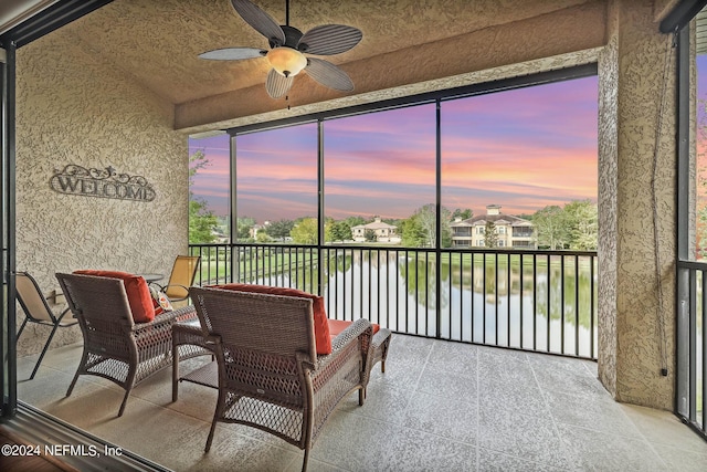 sunroom / solarium with ceiling fan and a water view