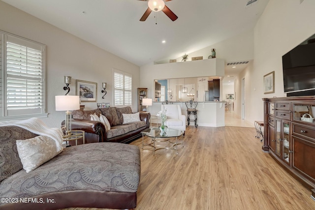 living room with ceiling fan, light hardwood / wood-style floors, and high vaulted ceiling