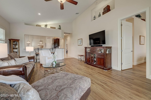 living room with ceiling fan, light hardwood / wood-style floors, and high vaulted ceiling