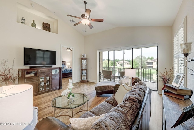 living room featuring ceiling fan, light hardwood / wood-style floors, and vaulted ceiling