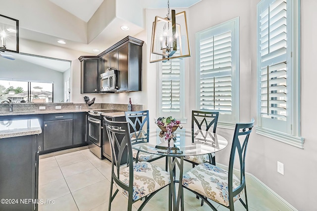 dining space with light tile patterned flooring, a chandelier, lofted ceiling, and sink