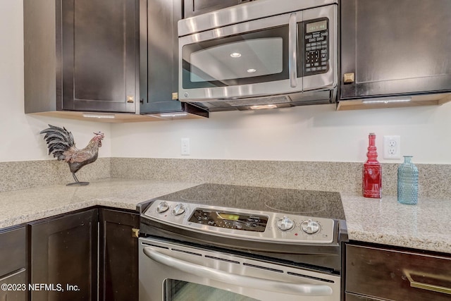 kitchen featuring dark brown cabinets, stainless steel appliances, and light stone counters