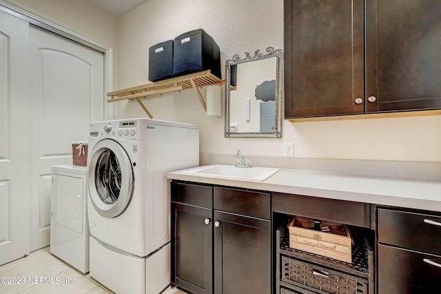 clothes washing area with separate washer and dryer, sink, light tile patterned floors, and cabinets