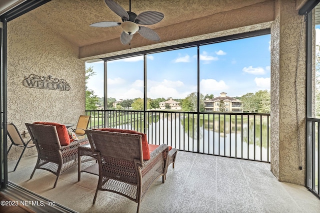 sunroom / solarium featuring ceiling fan and a water view