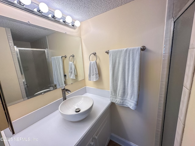 bathroom featuring a textured ceiling, a shower with shower door, and vanity