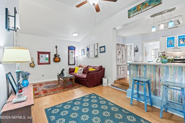 living room with a textured ceiling, hardwood / wood-style flooring, vaulted ceiling, and ceiling fan