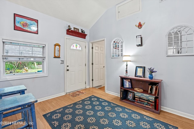 entrance foyer with wood-type flooring and vaulted ceiling