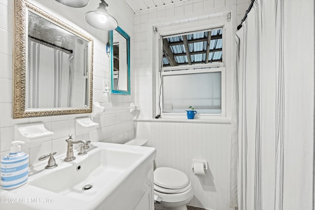 bathroom featuring curtained shower, toilet, sink, and wooden walls