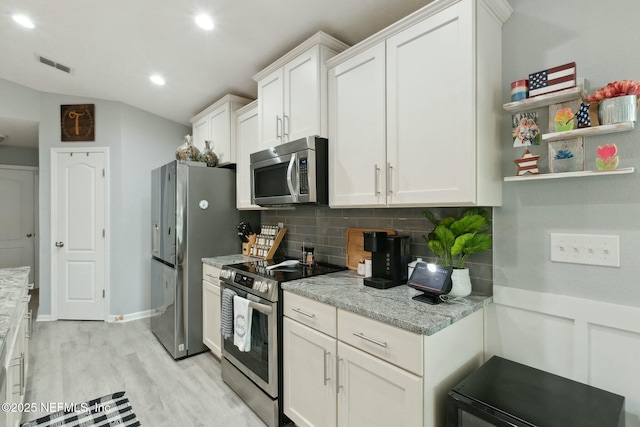 kitchen with light stone countertops, appliances with stainless steel finishes, tasteful backsplash, and white cabinetry