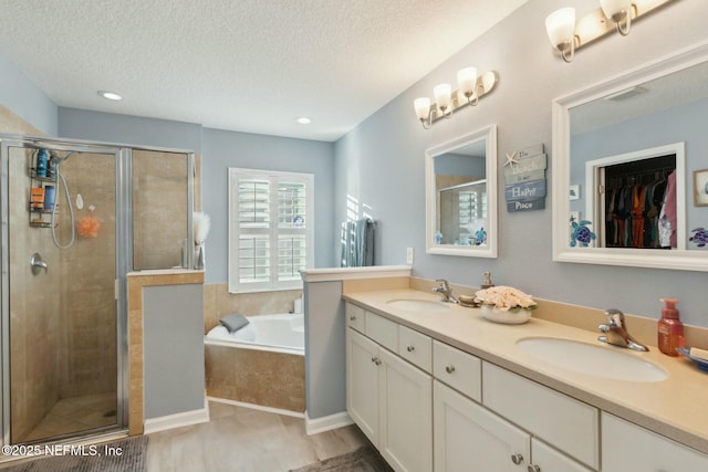 bathroom featuring vanity, a textured ceiling, and shower with separate bathtub