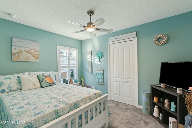 carpeted bedroom with ceiling fan, a closet, and a textured ceiling