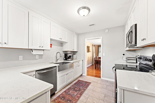 kitchen with light stone countertops, white cabinetry, sink, and appliances with stainless steel finishes