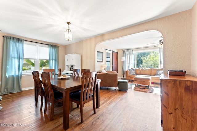 dining area featuring hardwood / wood-style floors, a barn door, and ceiling fan