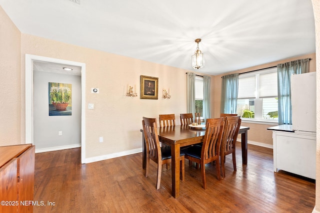 dining room with dark hardwood / wood-style floors and a notable chandelier