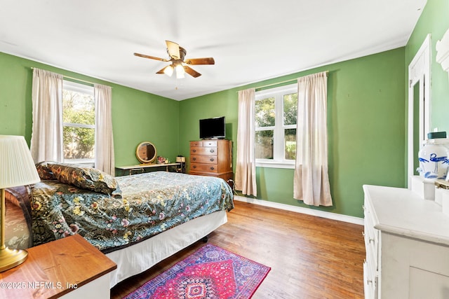 bedroom featuring ceiling fan, light hardwood / wood-style flooring, and multiple windows