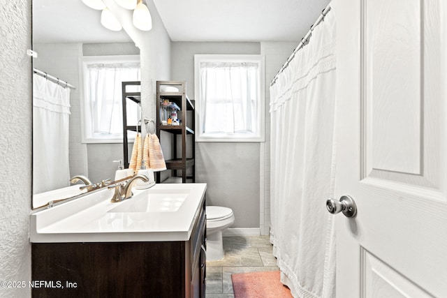 bathroom featuring plenty of natural light, toilet, and vanity