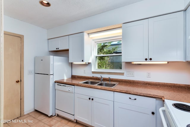 kitchen with a textured ceiling, sink, white cabinets, and white appliances