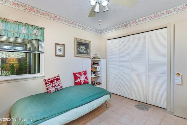 tiled bedroom with a textured ceiling, a closet, and ceiling fan