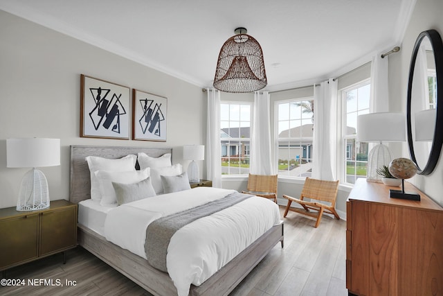 bedroom with hardwood / wood-style flooring, multiple windows, and crown molding