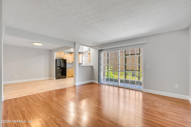 unfurnished living room with a healthy amount of sunlight, a textured ceiling, and light hardwood / wood-style flooring