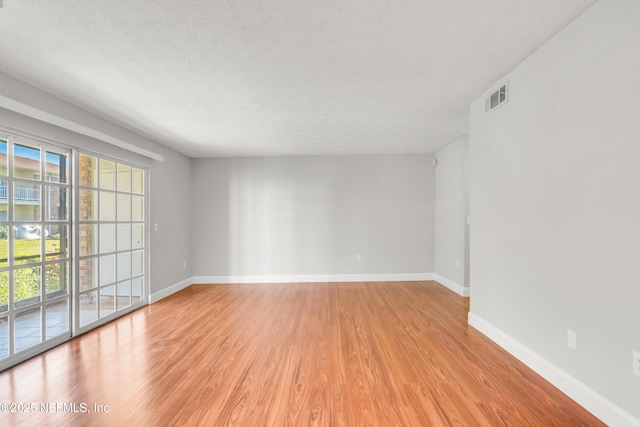 unfurnished room featuring a textured ceiling and light wood-type flooring