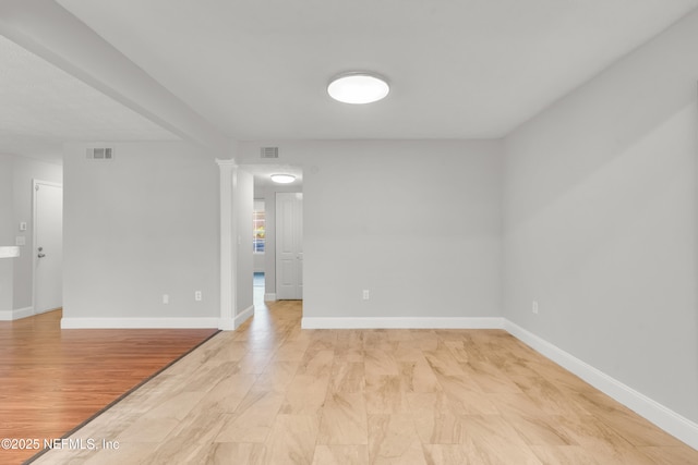 unfurnished room with light wood-type flooring and ornate columns