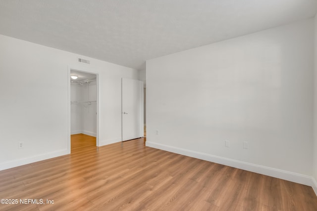 unfurnished bedroom with light hardwood / wood-style floors, a walk in closet, and a closet