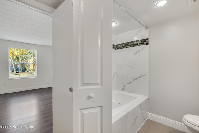 bathroom featuring toilet and tiled shower / bath