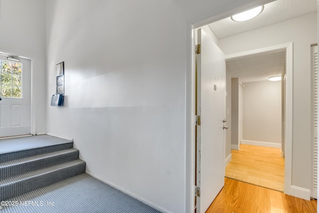 stairs with wood-type flooring and a textured ceiling