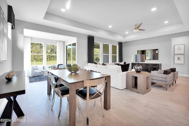 dining space featuring a raised ceiling, ceiling fan, and light tile patterned floors